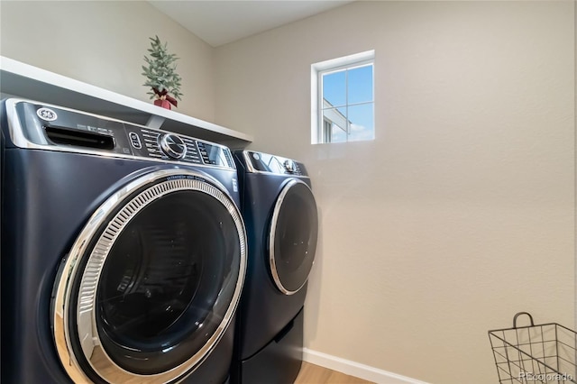 clothes washing area with washer and dryer, laundry area, wood finished floors, and baseboards