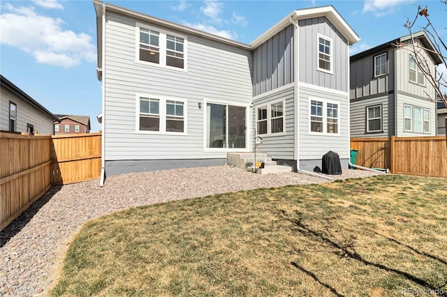 back of house featuring a lawn, board and batten siding, a fenced backyard, and entry steps