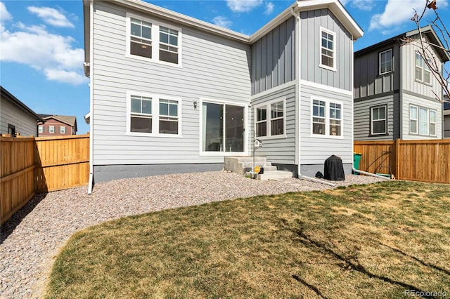 back of house featuring a lawn, board and batten siding, and a fenced backyard