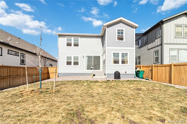 back of house featuring a yard, a fenced backyard, and board and batten siding