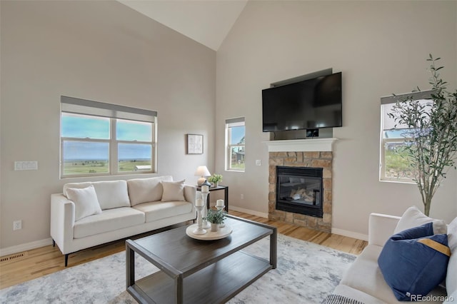 15580 Rigge Ct, Elbert, CO 80106 - living room with high vaulted ceiling, wood finished floors, baseboards, and a stone fireplace