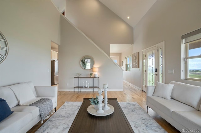 15580 Rigge Ct, Elbert, CO 80106 - living area featuring high vaulted ceiling, stairway, light wood-style flooring, and baseboards