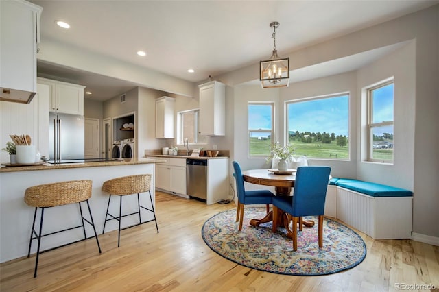 15580 Rigge Ct, Elbert, CO 80106 - dining room featuring separate washer and dryer, healthy amount of natural light, light wood finished floors, recessed lighting, and a chandelier