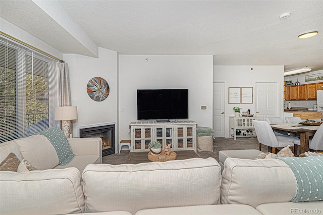 carpeted living area featuring a textured ceiling and a glass covered fireplace