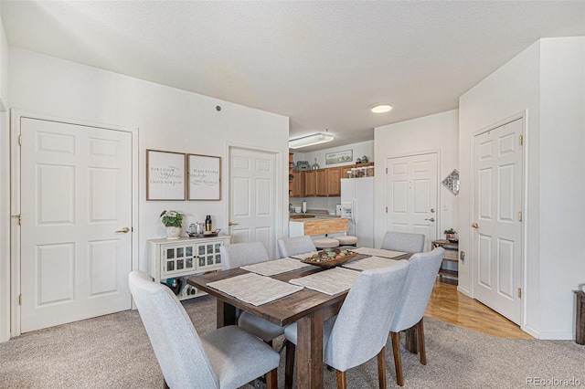 dining space featuring a textured ceiling and light colored carpet