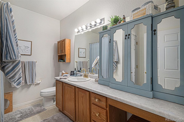 bathroom featuring baseboards, vanity, toilet, and tile patterned floors