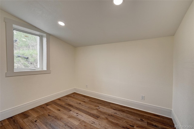 empty room with recessed lighting, baseboards, lofted ceiling, and wood finished floors