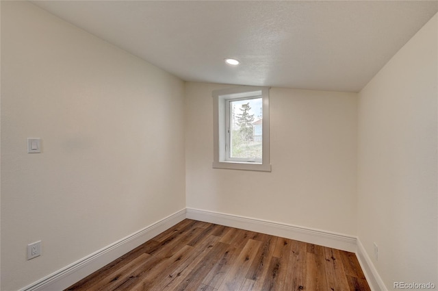 empty room with recessed lighting, lofted ceiling, baseboards, and wood finished floors