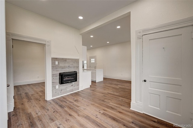 unfurnished living room with light wood finished floors, recessed lighting, a tile fireplace, and baseboards