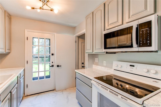 1170 Kingston St, Aurora, CO 80010 - kitchen featuring white appliances, light marble finish floors, a chandelier, and plenty of natural light