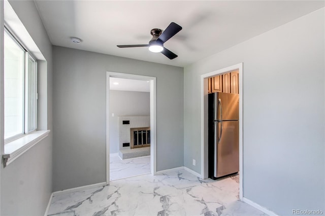 1170 Kingston St, Aurora, CO 80010 - unfurnished bedroom featuring freestanding refrigerator, light marble finish floors, a brick fireplace, and baseboards