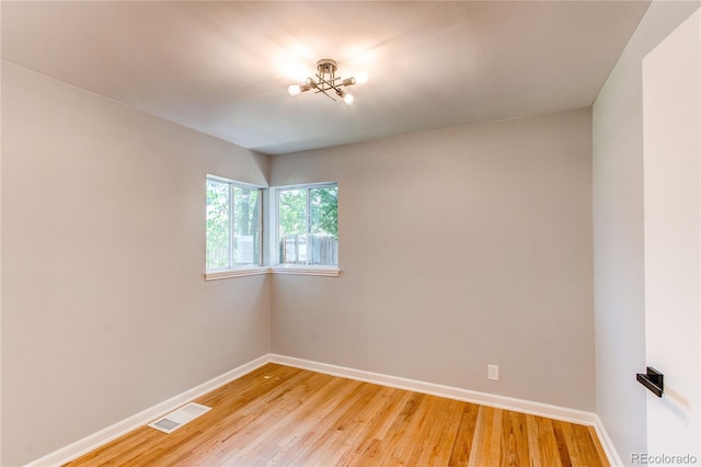 1170 Kingston St, Aurora, CO 80010 - unfurnished room with baseboards, light wood finished floors, and a chandelier