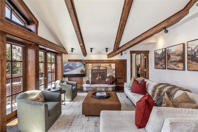 living room featuring french doors, a stone fireplace, and beamed ceiling