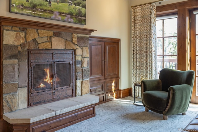 living area featuring a stone fireplace and carpet
