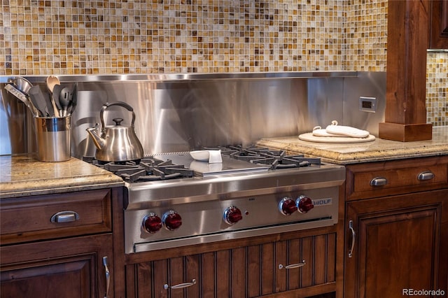 kitchen with backsplash, light stone countertops, and stainless steel gas stovetop