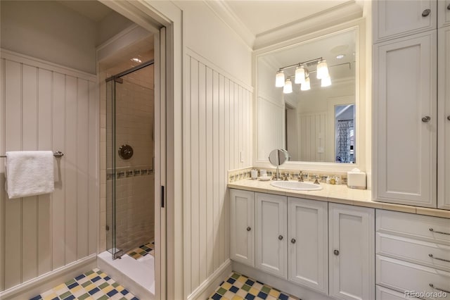 full bath featuring a shower stall, tile patterned floors, vanity, ornamental molding, and a decorative wall