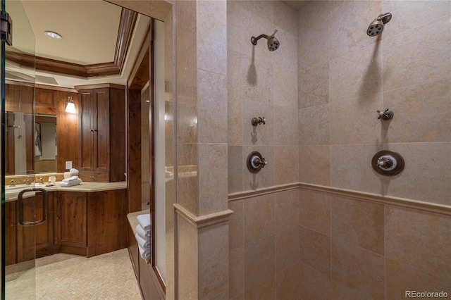full bathroom featuring a tile shower, ornamental molding, vanity, and a tray ceiling