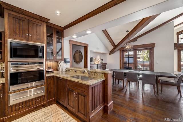 kitchen with a sink, a warming drawer, black microwave, light stone countertops, and stainless steel oven