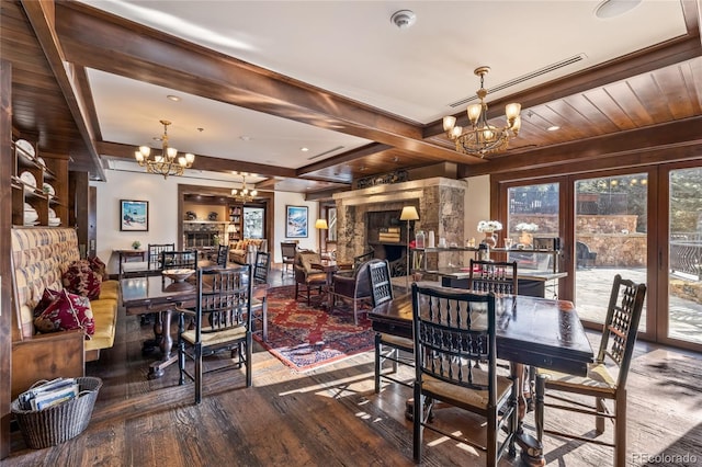 dining room featuring a notable chandelier, beam ceiling, wood finished floors, and a fireplace