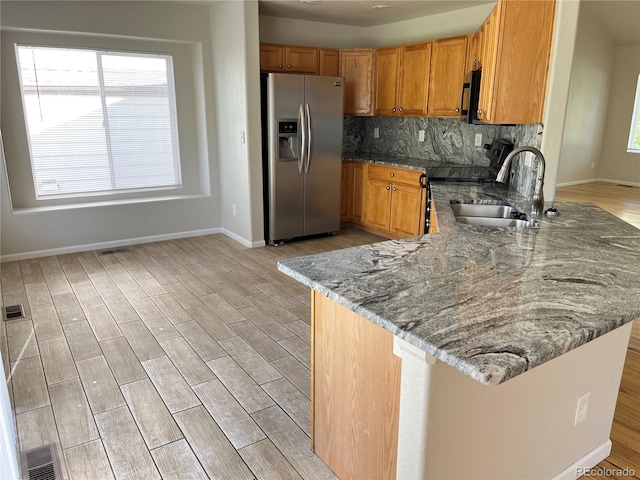 20558 E Grand Ln, Aurora, CO 80015 - kitchen featuring stainless steel refrigerator with ice dispenser, a sink, stone counters, a peninsula, and brown cabinetry