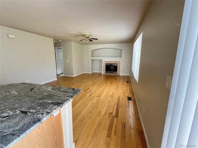 20558 E Grand Ln, Aurora, CO 80015 - unfurnished living room with a ceiling fan, light wood-type flooring, baseboards, and a tiled fireplace
