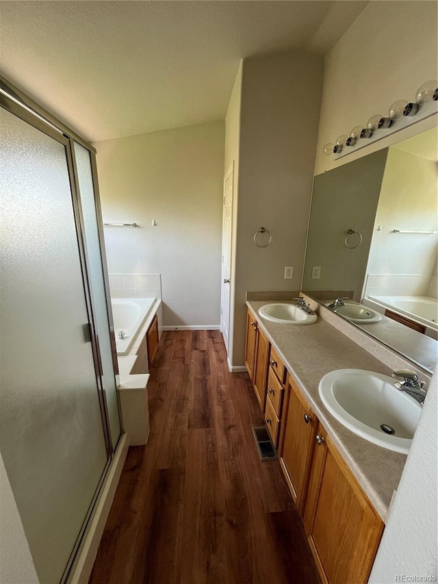 20558 E Grand Ln, Aurora, CO 80015 - full bathroom featuring a garden tub, wood finished floors, double vanity, a shower stall, and baseboards