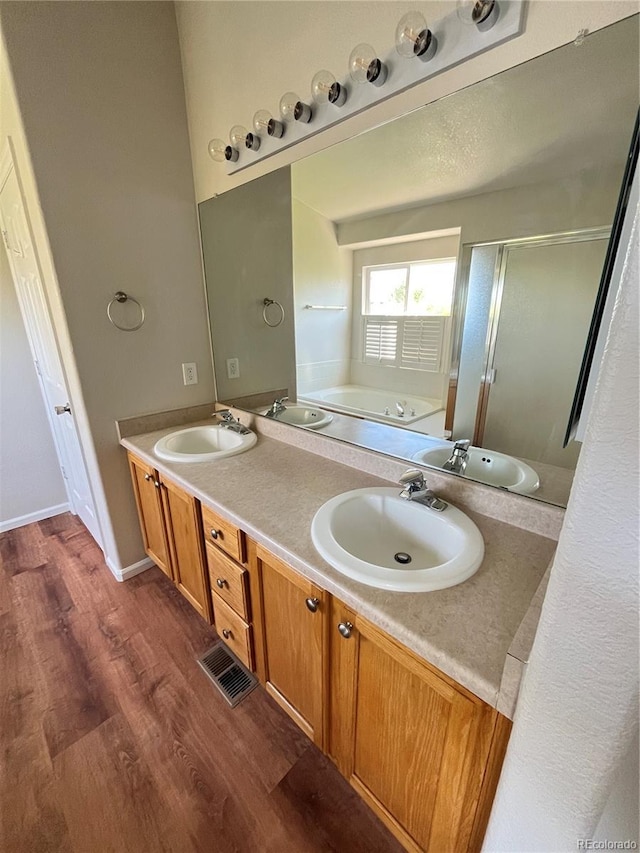 20558 E Grand Ln, Aurora, CO 80015 - bathroom featuring a garden tub, wood finished floors, double vanity, and a shower stall