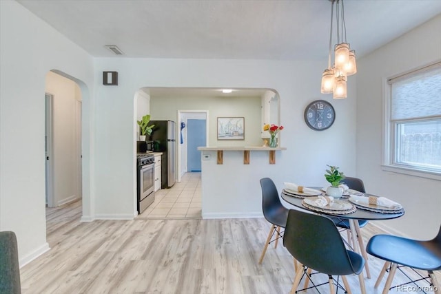 2684 S Logan St, Denver, CO 80210 - dining area featuring arched walkways, light wood-style floors, and baseboards