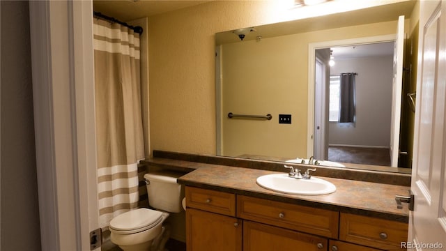 bathroom featuring a textured wall, vanity, and toilet