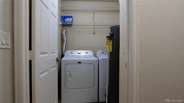 washroom with a textured wall, laundry area, and independent washer and dryer