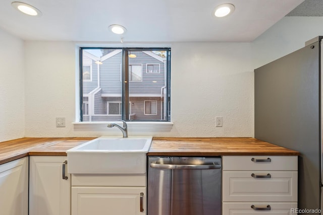 kitchen featuring stainless steel appliances, white cabinets, sink, and butcher block counters