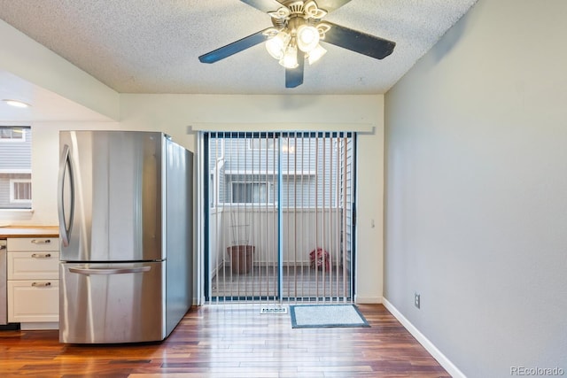 kitchen featuring ceiling fan, white cabinets, a textured ceiling, dark wood-type flooring, and stainless steel refrigerator