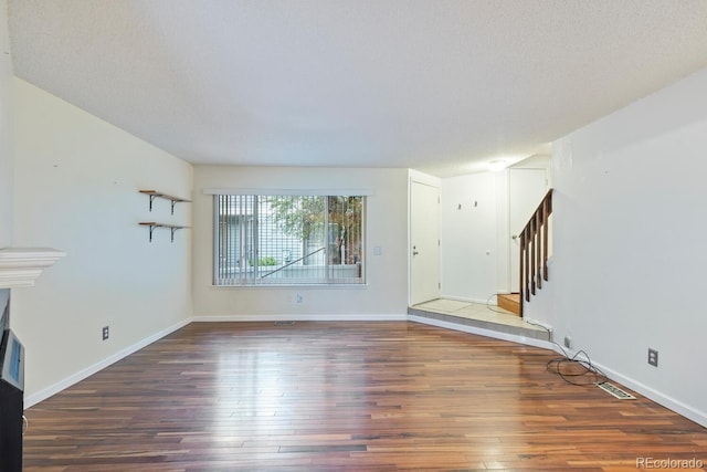 unfurnished living room with a textured ceiling and dark wood-type flooring