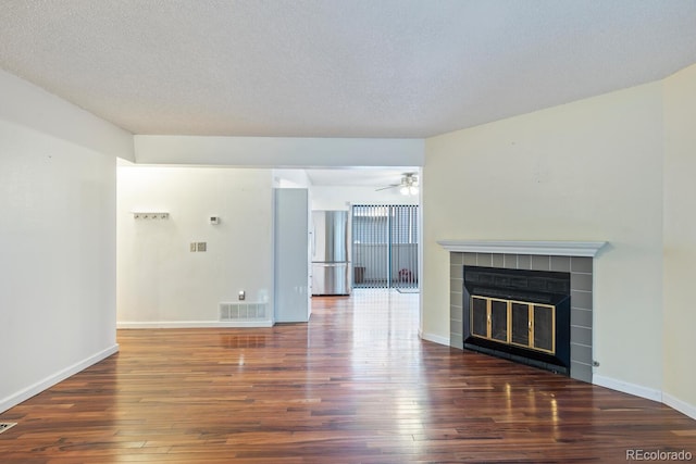 unfurnished living room featuring ceiling fan, a textured ceiling, a fireplace, and dark hardwood / wood-style flooring