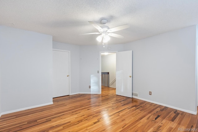 spare room with light hardwood / wood-style floors, a textured ceiling, and ceiling fan