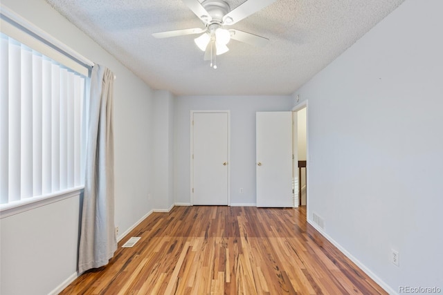 unfurnished bedroom with wood-type flooring, a textured ceiling, and ceiling fan