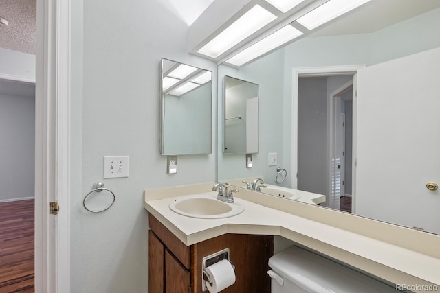 bathroom featuring hardwood / wood-style flooring, toilet, and vanity