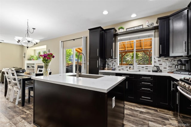 139 N Prairie Falcon Pkwy, Brighton, CO 80601 - kitchen with dark cabinetry, a sink, a center island with sink, plenty of natural light, and recessed lighting