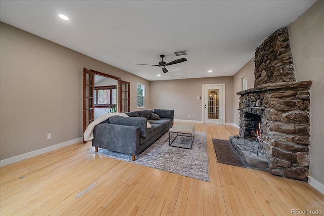 living area with ceiling fan, visible vents, a fireplace, baseboards, and hardwood / wood-style floors