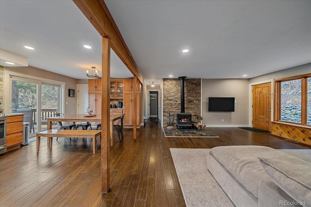living room featuring recessed lighting, baseboards, a wood stove, and dark wood-type flooring