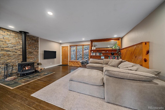 living room featuring baseboards, a wood stove, recessed lighting, and hardwood / wood-style floors