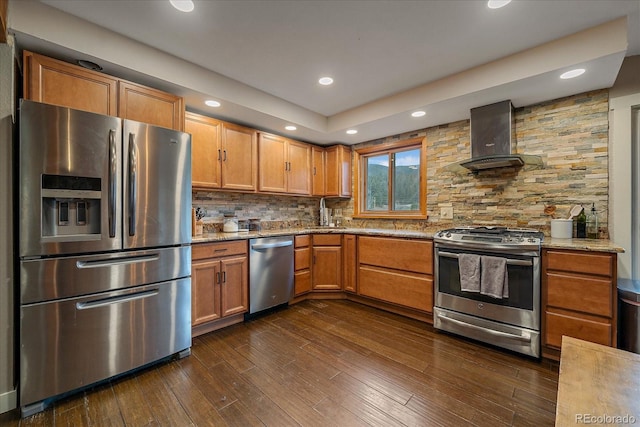 kitchen with light stone counters, decorative backsplash, stainless steel appliances, and island range hood