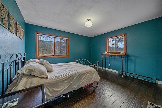 bedroom featuring baseboards, a baseboard radiator, and hardwood / wood-style flooring