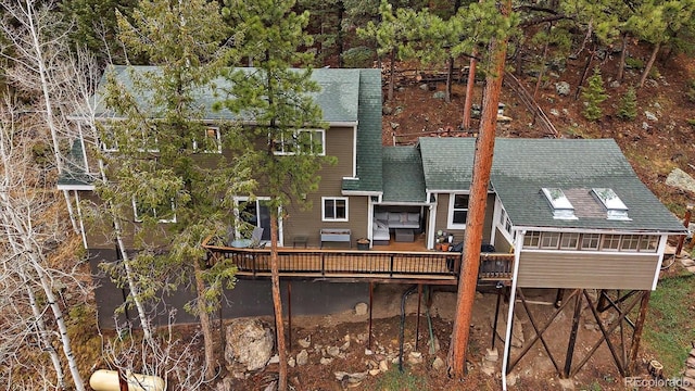 rear view of property featuring roof with shingles and a deck