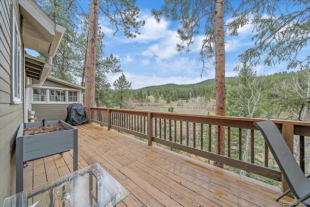 wooden terrace featuring a mountain view and a forest view