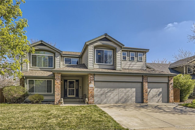 traditional home featuring a front yard, a shingled roof, driveway, and a garage