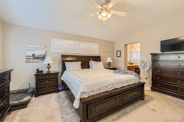 bedroom with vaulted ceiling, light carpet, ensuite bath, and a ceiling fan