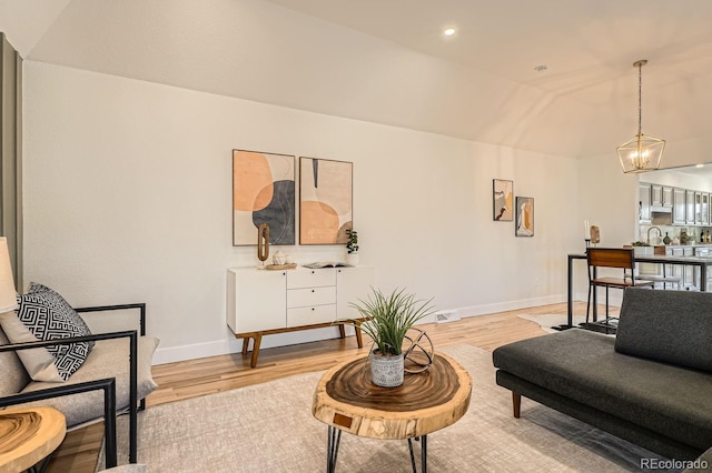 living room featuring lofted ceiling, a chandelier, and light hardwood / wood-style floors