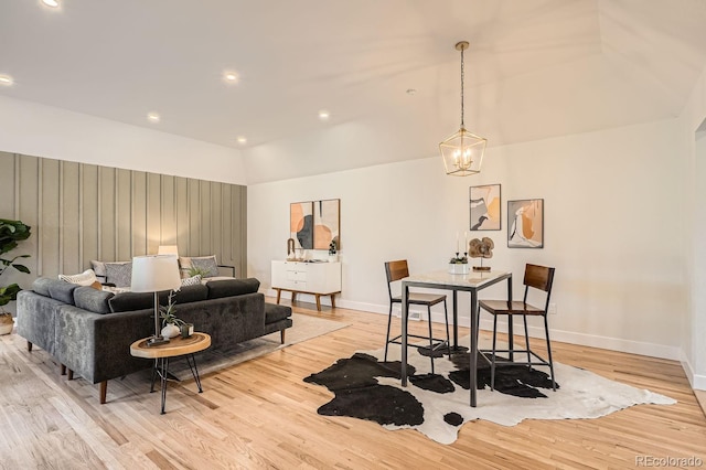 living room featuring lofted ceiling, a chandelier, and light hardwood / wood-style floors