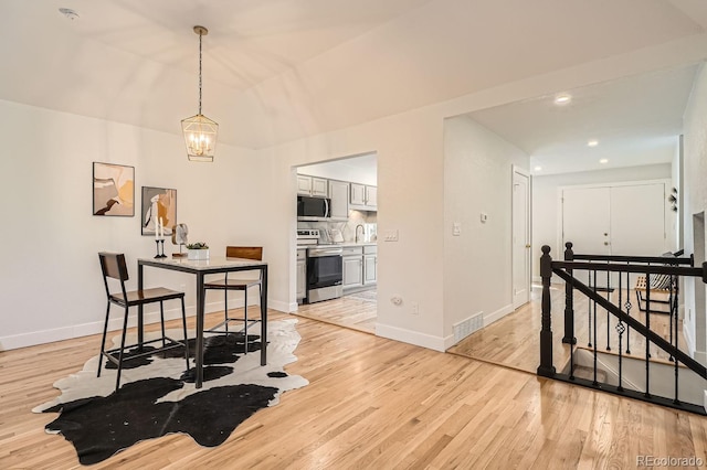 dining room with sink, an inviting chandelier, and light hardwood / wood-style floors